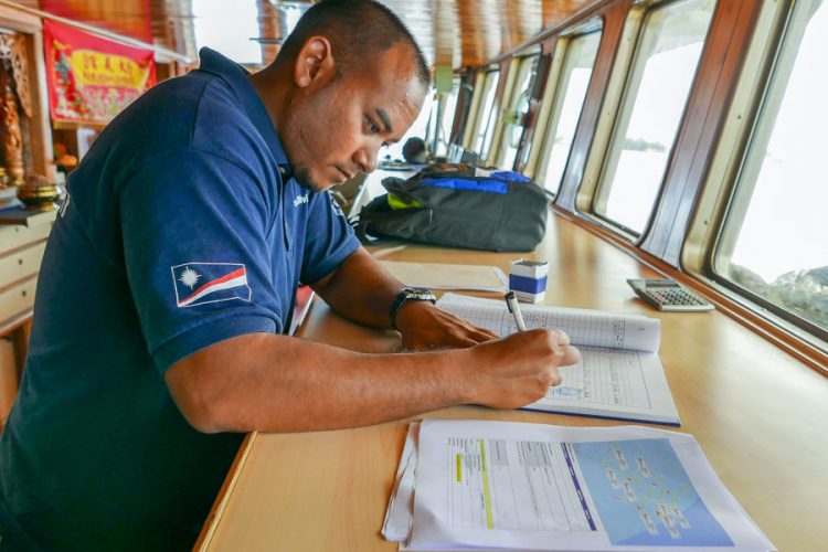 Fisheries officer checks documents on a fishing vessel that seeks access to the port of Majuro, Marshall Islands. Photo Francisco Blaha.