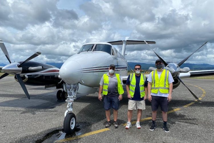 The PMSP/FFA aircraft on tarmac in Honiara, Solomon Islands, with three men standing beside it