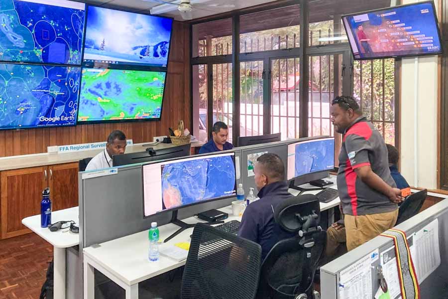 Four men looking at computer screens in FFA Regional Fisheries Surveillance Centre during Operation Kurukuru 2021