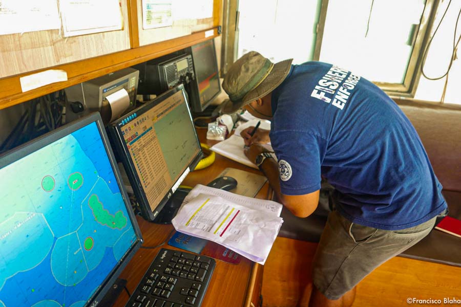 Marshall Islands fisheries officer Beau Bigler cross-checks issues identified in his Arriving Vessel Intelligence Report with the vessel’s GPS and eFAD plotters, catch log-sheets and logbooks, before he will authorise the vessel to use Majuro Port. Photo: Francisco Blaha.